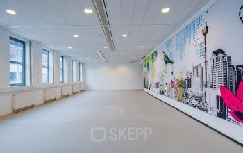 Een ruime, lichte kantoorruimte op De Wel 20, Hoevelaken, met grote ramen en een kleurrijke muurschildering. Perfect voor wie een moderne en inspirerende kantoorpand zoekt om te huren.