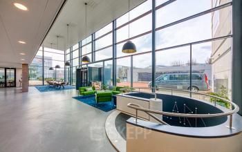 Foto van de lichte en moderne ontvangstruimte van het kantoorpand op Polarisavenue 130-150 in Hoofddorp, met grote ramen, zitgedeelte en uitzicht op de buitenruimte.