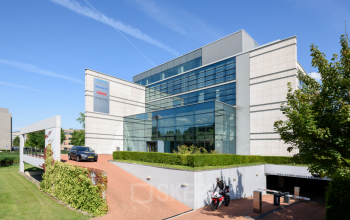 Modern kantoorpand op Polarisavenue 130-150, Hoofddorp. Glazen entree met groenvoorziening en parkeerplaatsen aanwezig.