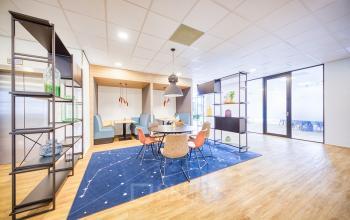 Modern ingerichte kantoorruimte met lichte houten vloeren, een blauw vloerkleed en kleurrijke stoelen aan Polarisavenue 130-150, Hoofddorp.