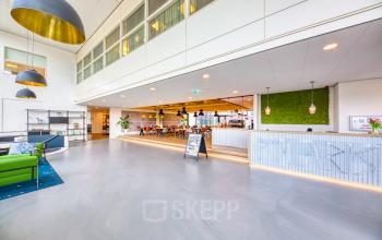 Interieur van kantoorpand op Polarisavenue 130-150 in Hoofddorp. Ruime entree met moderne inrichting en veel zitplekken. Verschillende mensen aan het werk of in gesprek.
