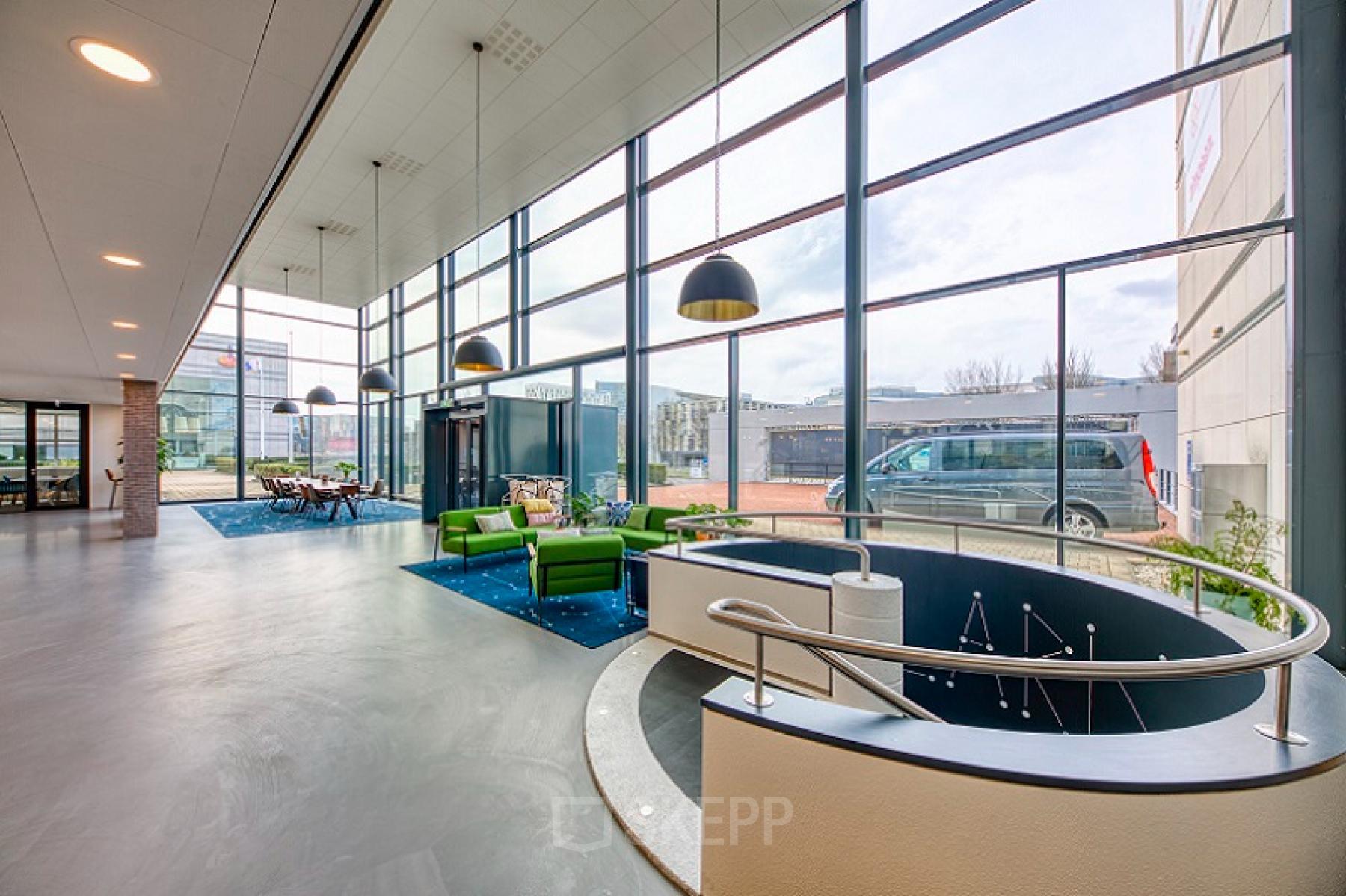 Foto van de lichte en moderne ontvangstruimte van het kantoorpand op Polarisavenue 130-150 in Hoofddorp, met grote ramen, zitgedeelte en uitzicht op de buitenruimte.