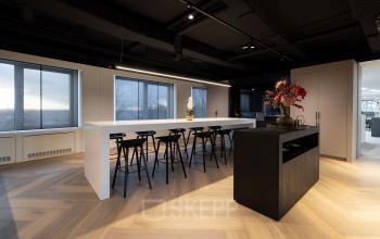 Kantoorruimte huren op Polarisavenue 1, Hoofddorp: moderne werkplekken met hoge tafels en krukken, minimalistisch interieur, grote ramen voor natuurlijk licht.
