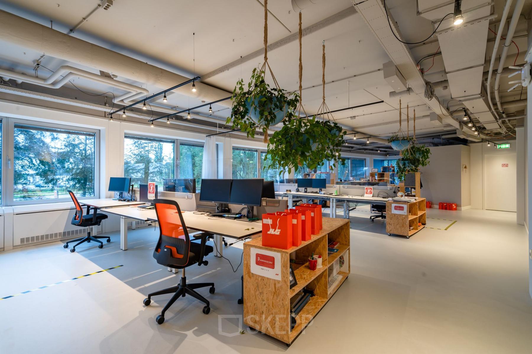 Moderne kantoorruimte huren op Polarisavenue 1, Hoofddorp; ingericht met bureaus, stoelen en groene planten, voorzien van grote ramen voor natuurlijk licht.