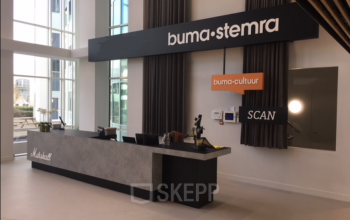Ruime entree in kantoorpand op Saturnusstraat 40-62, Hoofddorp, met moderne receptiebalie onder Buma-Stemra borden. Grote ramen zorgen voor veel lichtinval.