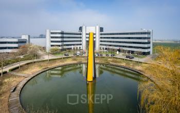 Kantoorpand Hoeksteen 54-72 in Hoofddorp met moderne architectuur, gesitueerd rondom een vijver. Ideaal voor kantoorruimte huren.