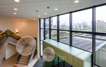 Moderne, ruime hal van een kantoorpand aan de Hoeksteen 54-72 in Hoofddorp, met grote ramen en stijlvolle verlichting.