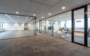Modern ingerichte kantoorruimte in kantoorpand Hoeksteen 54-72, Hoofddorp met glazen scheidingswanden en comfortabel meubilair.