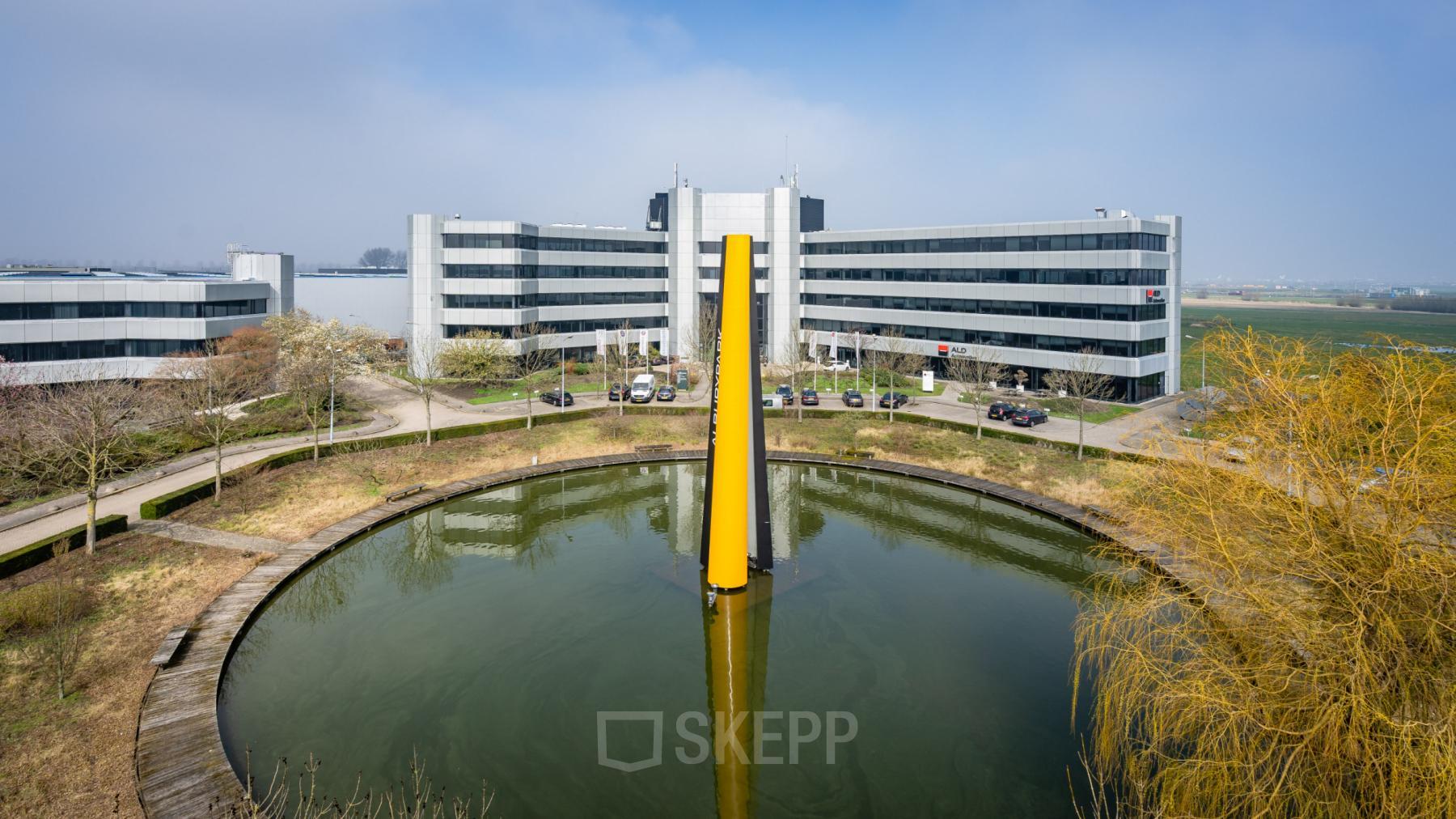 Kantoorpand Hoeksteen 54-72 in Hoofddorp met moderne architectuur, gesitueerd rondom een vijver. Ideaal voor kantoorruimte huren.