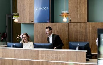 Twee mensen achter een receptiebalie in een kantoorpand op Mercuriusplein 1, Hoofddorp, bezig met administratieve werkzaamheden. De moderne receptie is onderdeel van een professioneel kantoor.