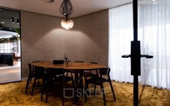 Vergaderruimte in kantoorpand op Mercuriusplein 1, Hoofddorp, met houten tafel en stoelen, zachte verlichting en moderne inrichting voor huur.