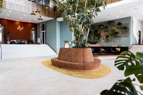 Moderne kantoor ingericht met glazen wanden, veel groen en een grote ronde bank bij de ingang aan Mercuriusplein 1 in Hoofddorp. Ideaal voor wie een kantoorpand wilt huren.