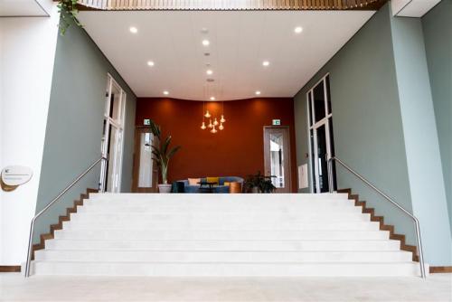 Ingang van het kantoorpand op Mercuriusplein 1, Hoofddorp met moderne entree en trap naar boven. Stijlvolle verlichting en decoratieve elementen in een uitnodigende omgeving.