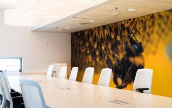 Moderne vergaderruimte in kantoorpand Hoofddorp op Opaallaan 1180, met een opvallende muurdecoratie en stijlvolle witte stoelen. Ideaal voor bedrijven die kantoorruimte willen huren voor zakelijke bijeenkomsten.