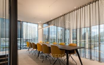 Ruime vergaderruimte in een kantoorpand aan de Taurusavenue 1-41 in Hoofddorp, voorzien van een lange tafel en gele stoelen, geschikt voor zakelijke ontmoetingen.