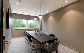 Moderne vergaderruimte met glazen tafel, diverse stoelen en grote ramen in kantoorpand aan de Taurusavenue 1-41 in Hoofddorp. Ideaal voor kantoorruimte huren.