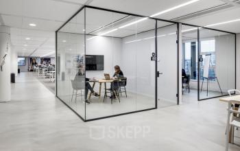 Moderne kantoorruimte op Siriusdreef 16 in Hoofddorp met glazen wanden en werkende personen aan tafels, ideaal voor kantoor huren en flexibele werkplekken.