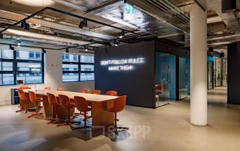 Moderne kantoorruimte op Siriusdreef 16 in Hoofddorp met een lange tafel en oranje stoelen, geschikt voor vergaderingen of teamwerk. De muur heeft inspirerende tekst, ideaal voor wie kantoorruimte wil huren.