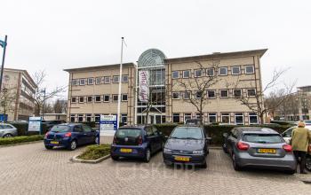 Kantoorpand aan Siriusdreef 17 in Hoofddorp, met een moderne glazen ingang en parkeergelegenheid voor het huren van kantoorruimte.