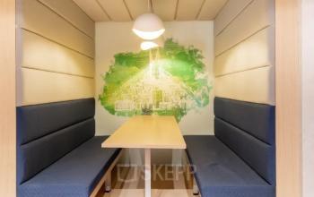 Moderne vergaderruimte met houten tafel en blauwe zitbanken in kantoor aan Siriusdreef 17, Hoofddorp. Geschikt voor ondernemers die kantoorruimte willen huren.