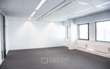 Ruime en lichte kantoorruimte in Houten met grote ramen en grijze vloerbedekking, ideaal voor het huren van een modern kantoorpand.