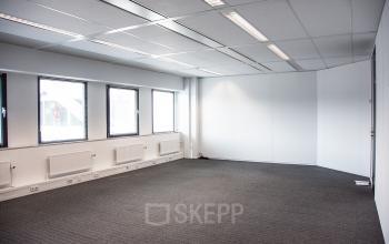 Lichte kantoorruimte met grote ramen en grijze vloerbedekking op Meidoornkade 19 in Houten, ideaal om als kantoor te huren.