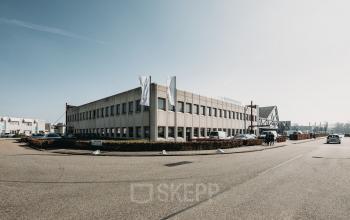 Grijs kantoorpand aan de Meidoornkade 22 in Houten met parkeerplaatsen en vlaggenstokken aan de voorzijde.