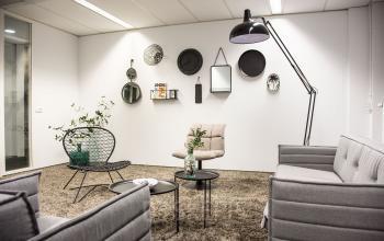 Stijlvolle kantoorruimte huren aan de Meidoornkade 22 in Houten, ingericht met comfortabele banken, moderne metalen decoraties aan de muur, en een zachte grijze vloerbedekking.