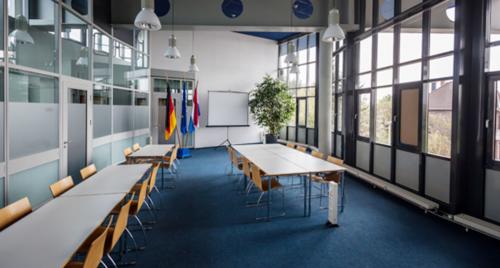 Vergaderruimte in kantoorpand op Eurodepark 1, Kerkrade. De ruimte heeft grote ramen, moderne verlichting en witte tafels met houten stoelen. Kantoorruimte huren met ruime en lichte inrichting.