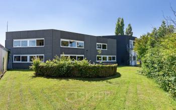 Tweedelig grijs kantoorpand op Ouddeelstraat 7a in Leeuwarden met groene omliggende tuin.