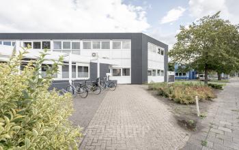 Exterieur van het kantoorpand op Ouddeelstraat 7a, Leeuwarden met een moderne uitstraling, omgeven door stenen bestrating en groenvoorzieningen.