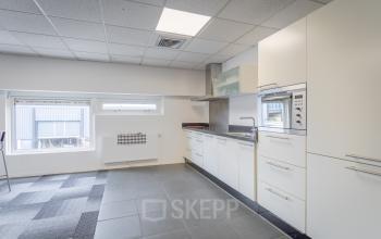 Moderne pantry in het kantoorpand aan de Ouddeelstraat 7a in Leeuwarden, met wittinten en grijs betegelde vloer; perfect ingericht voor wie een kantoorruimte wil huren.