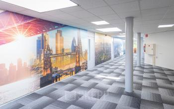 Lange gang in het kantoorpand op Ouddeelstraat 7a in Leeuwarden, met kleurrijke wanddecoratie en grijs gestreept tapijt, klaar voor kantoorruimte huren.