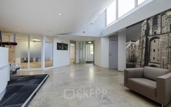 Ruime entree van een kantoorpand op Ouddeelstraat 7a, Leeuwarden. Grote ramen zorgen voor veel lichtinval. De ruimte heeft een strakke, moderne uitstraling. Ideaal voor wie een kantoorruimte wil huren in Leeuwarden.