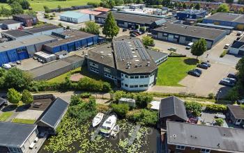 Luchtfoto van een kantoorpand aan de Ouddeelstraat 7a in Leeuwarden, omringd door groen en met parkeergelegenheid op het terrein. Ideaal voor kantoorruimte huren.
