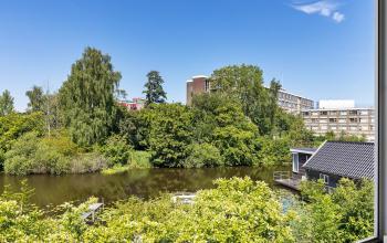 Uitzicht op de groene omgeving van kantoorpand aan de Ouddeelstraat 7a, Leeuwarden, met water en omringende gebouwen.