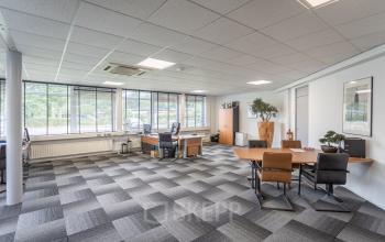 Kantoorruimte te huur op Ouddeelstraat 7a, Leeuwarden. Lichte werkruimte met modern tapijt, grote ramen aan rondt het kantoor. Meerdere bureaus en stoelen aanwezig voor diverse werkplekken in een ruime indeling.