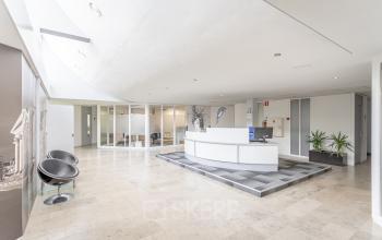 Moderne en lichte receptieruimte met een ontvangsbalie in het kantoorpand aan Ouddeelstraat 7a, Leeuwarden. Ruime indeling met glazen wanden en stijlvolle meubels, ideaal voor kantoorruimte huren.