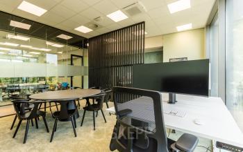 Kantoorruimte huren op Lange Marktstraat 1 in Leeuwarden met werkruimte, vergadertafel, stoelen en monitor in een modern kantoorpand met glazen wanden.