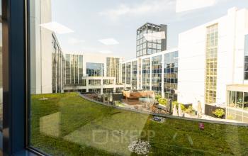 Uitzicht vanuit Lange Marktstraat 1, Leeuwarden, met moderne kantoorpanden en groene daken.