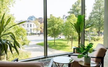 Kantoorruimte huren in Leeuwarden, Lange Marktstraat 1, met groen uitzicht door grote ramen, twee stoelen en planten.