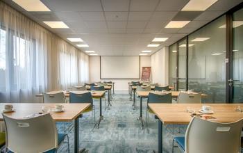 Modern kantoorpand op Schipholweg 103, Leiden, met glazen wanden en opstelling van bureaus en stoelen klaar voor een vergadering, voorzien van een projector en koffiekopjes
