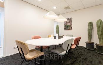 Vergaderruimte in kantoorpand aan Pompoenweg 3 - 15, Leiden. Moderne, lichte ruimte met ovale tafel, stoelen en twee grote cactussen. Kantoorruimte huren in een goed ingerichte omgeving.