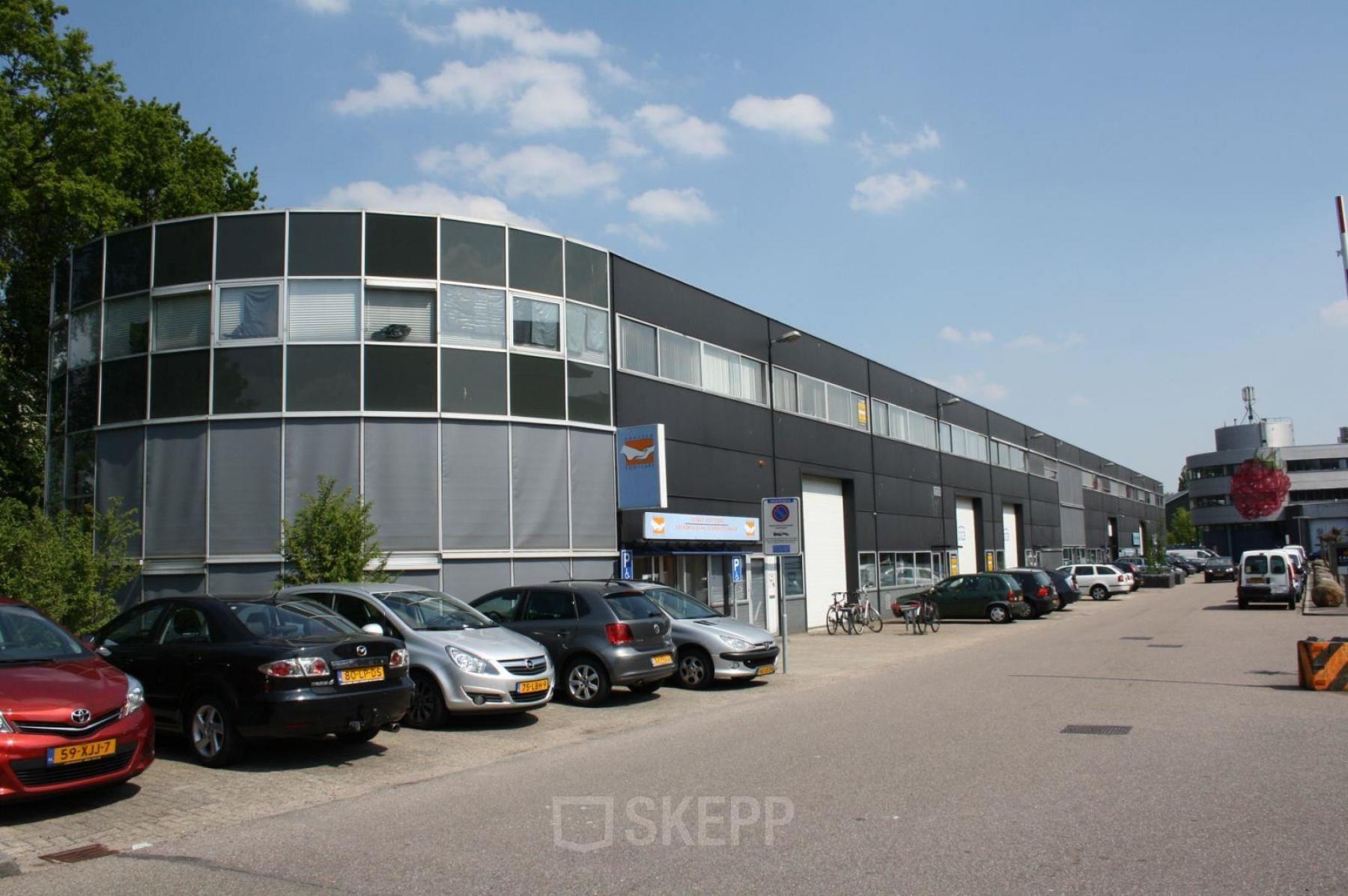 Een modern kantoorpand aan de Fruitweg 22 in Leiden, met verschillende geparkeerde auto's langs de straat. Ideaal voor bedrijven die kantoorruimte willen huren.