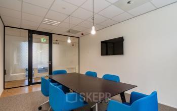 Vergaderruimte te huur met blauwe stoelen en een groot scherm, Schipholweg 55-89, Leiden.