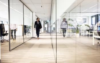 Modern kantoorpand gelegen op Kanaalpark 140, Leiden, met ruime werkplekken, glazen scheidingswanden en actieve medewerkers.