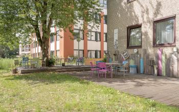 Modern kantoorpand op Kanaalpark 157 in Leiden, voorzien van een sfeervol ingerichte ontmoetingsplek buiten met diverse stoelen en tafels.
