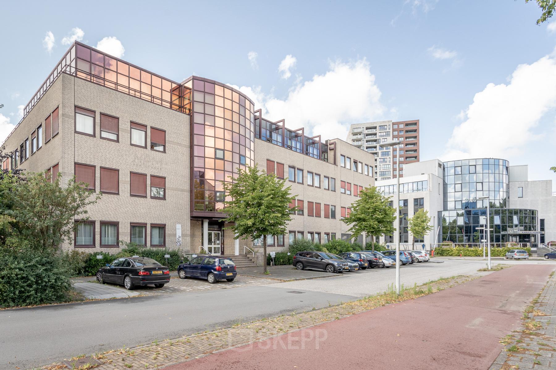 Vooraanzicht van het kantoorpand op Kanaalpark 157, Leiden, met parkeerplaatsen en meerdere auto's ervoor.