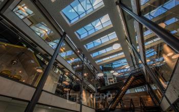 Moderne en industriële kantoorruimte in het kantoorpand op Fokkerstraat 16 in Leusden met glazen wanden, hoge plafonds en zicht op meerdere etages binnen het gebouw.