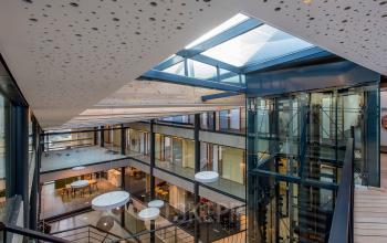 Binnenkant kantoor op Fokkerstraat 16, Leusden met ruime open vloerplannen, veel natuurlijke lichtinval door glazen plafonds, en moderne glazen liften. Ideaal voor kantoorruimte huren met stijl en comfort.